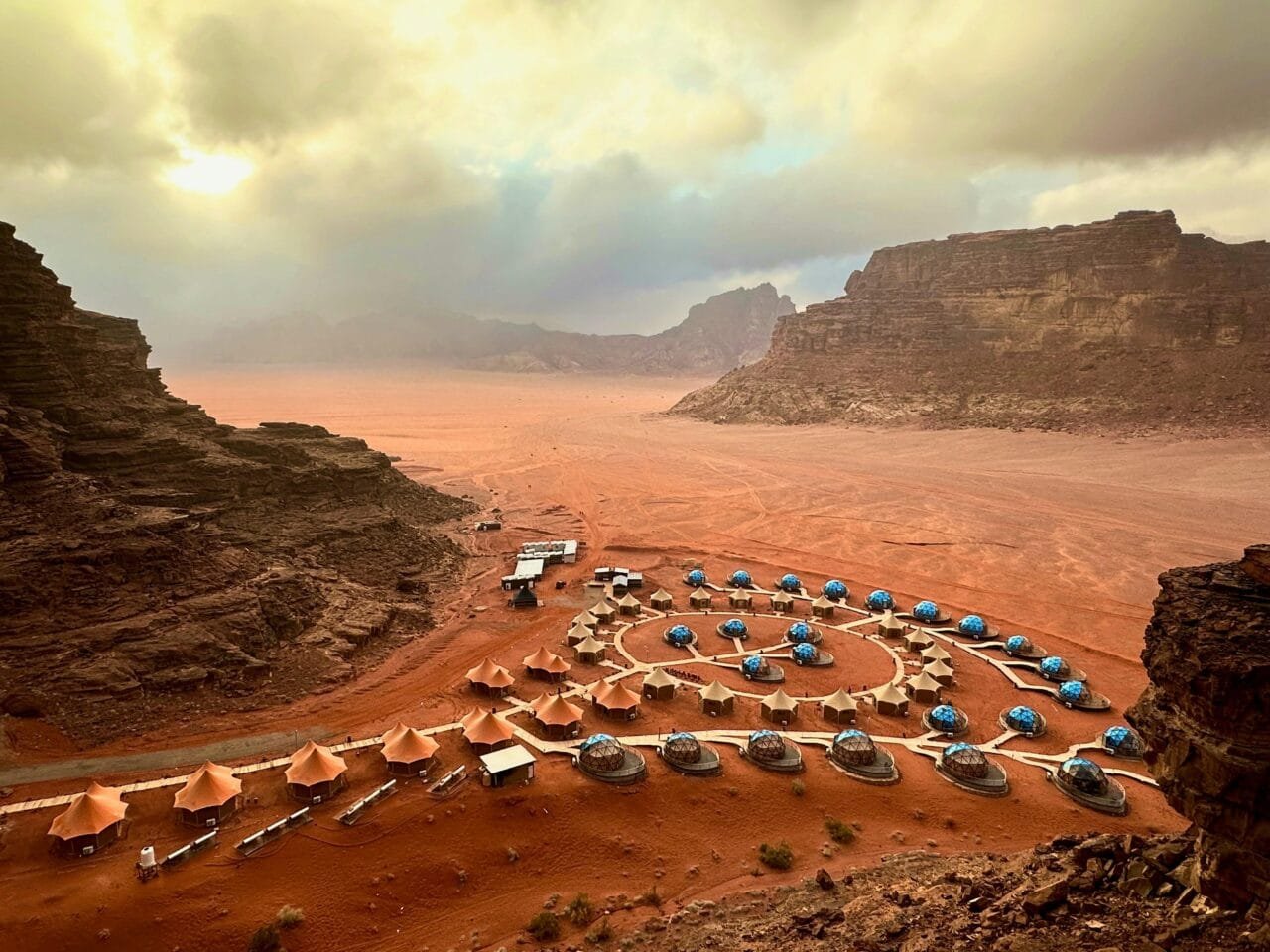 Breathtaking view of Wadi Rum's desert landscape with towering red sandstone cliffs, vast sand dunes, and a clear blue sky in southern Jordan